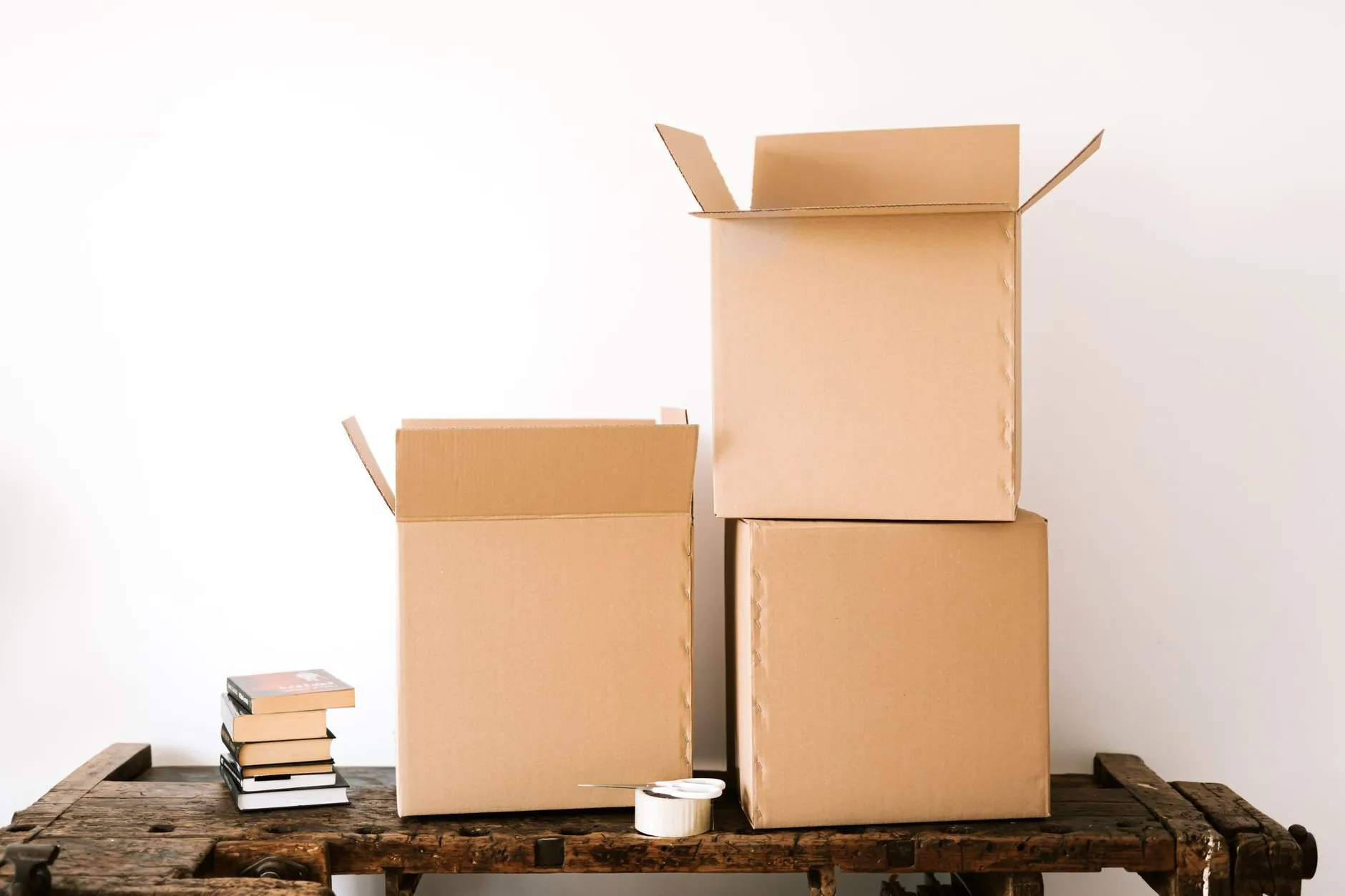 Empty cardboard boxes and a stack of books on an old wooden workbench ready to be packed