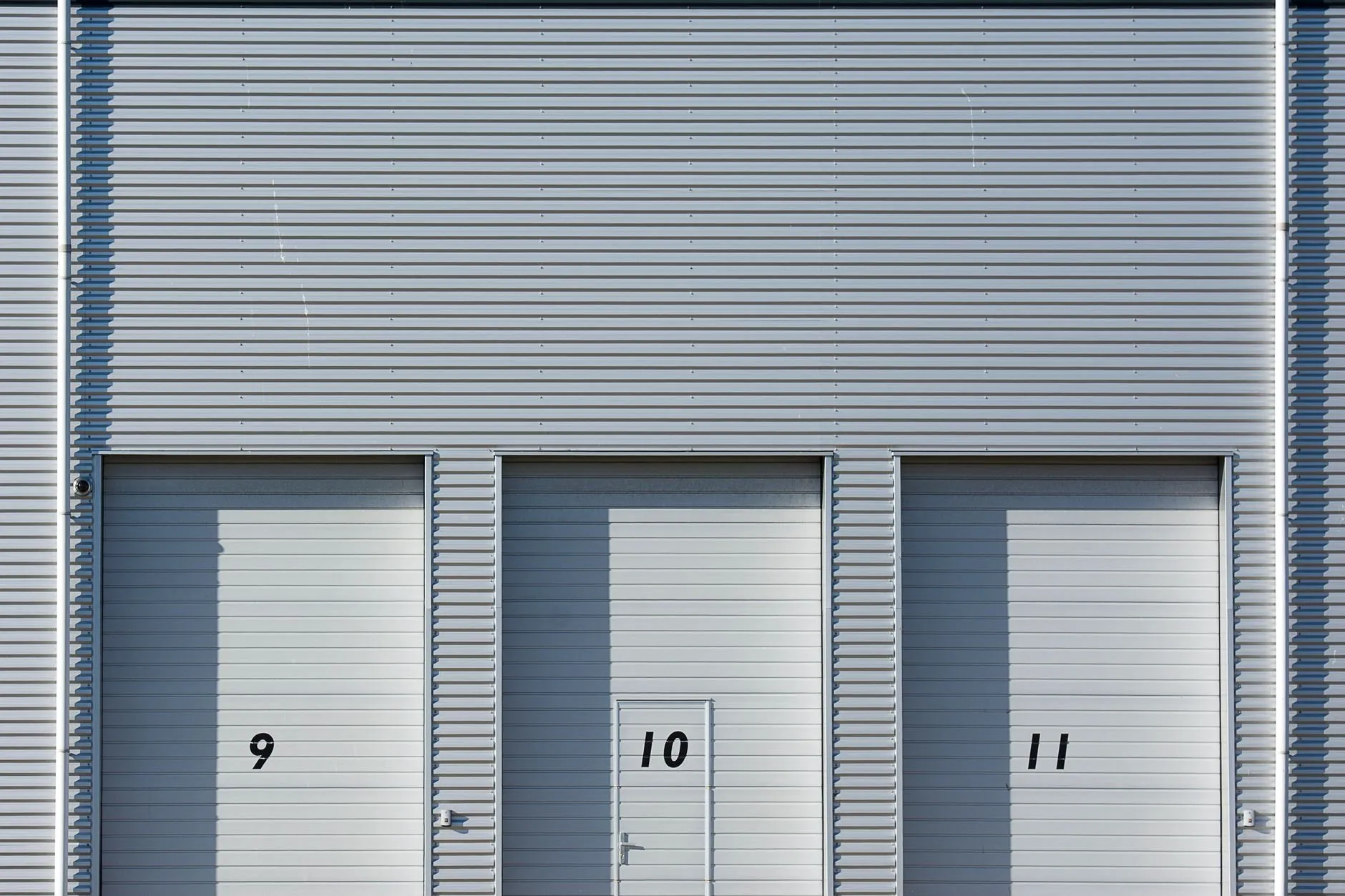 Three pale grey roll-up doors numbered 9, 10 and 11