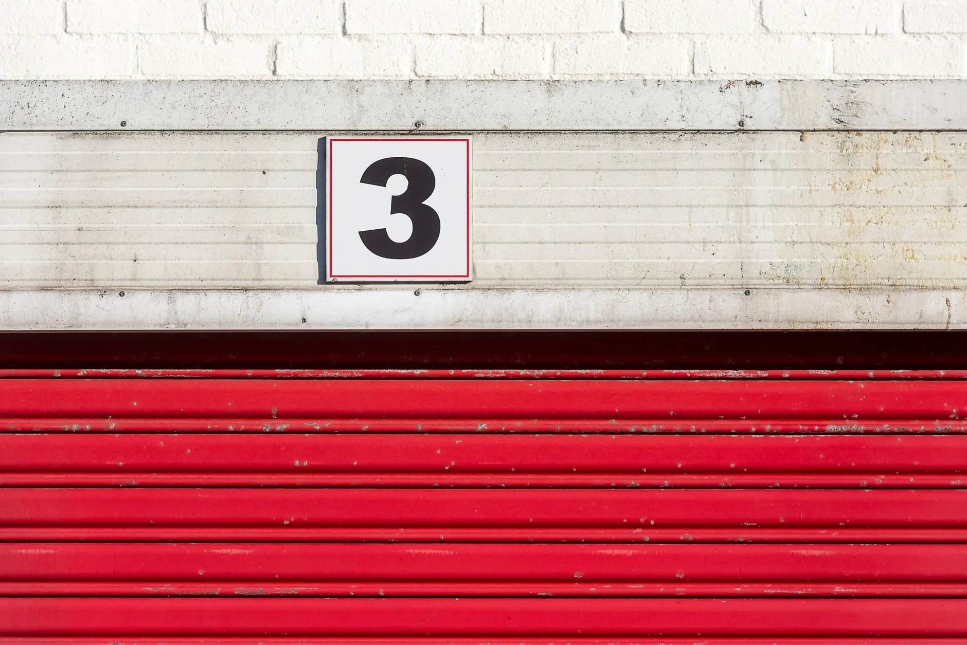 A red roller door below a white unit number sign reading 3