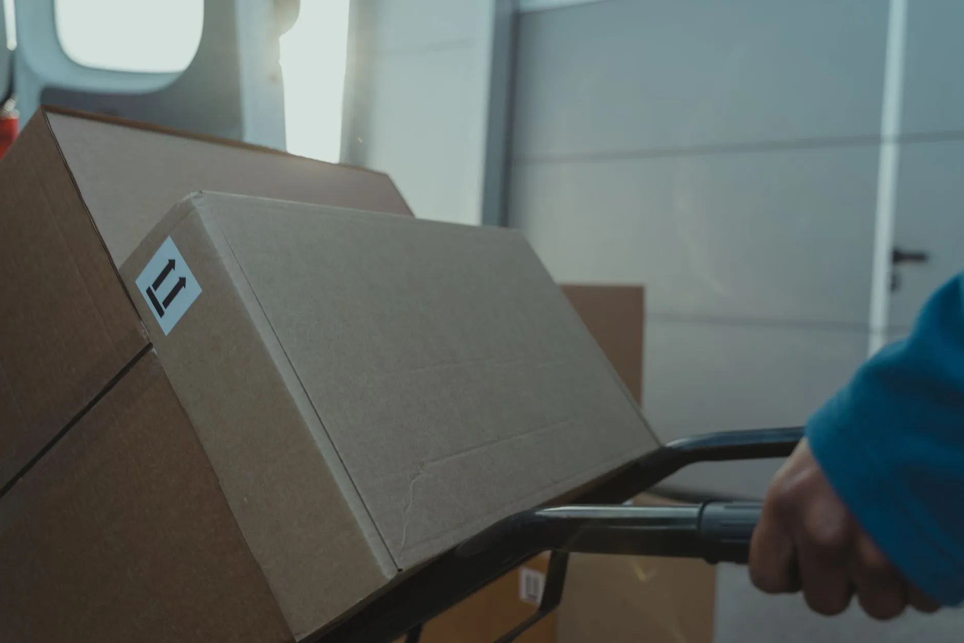 A sack truck loaded with boxes at the back of a van